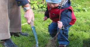 A grandparent helping his grandchild plant a tree